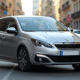Voiture Peugeot 308 argentée en ville en plein jour